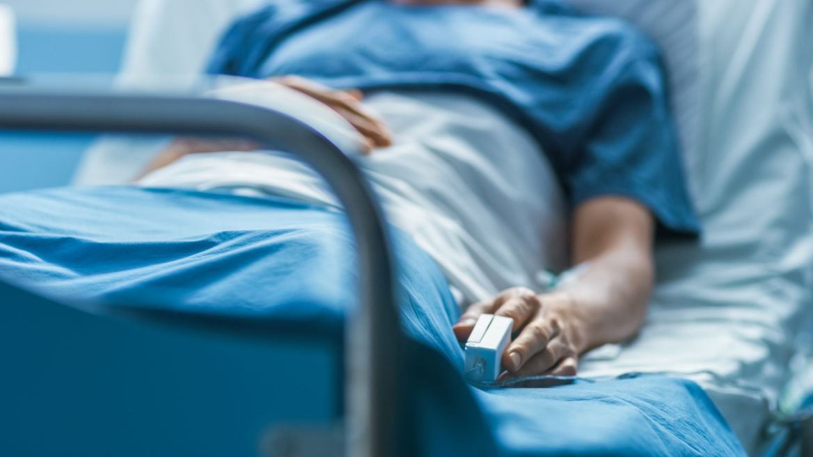 E.coli lawyer - patient in hospital bed with monitor in finger