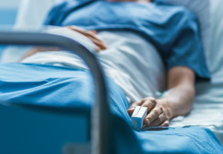 E.coli lawyer - patient in hospital bed with monitor in finger