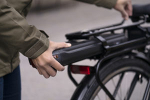Woman attaching battery on an electric bike