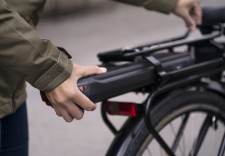 Woman attaching battery on an electric bike