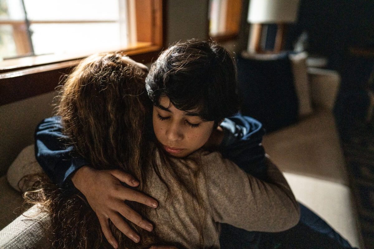 Mother embracing and consoling sad son at home