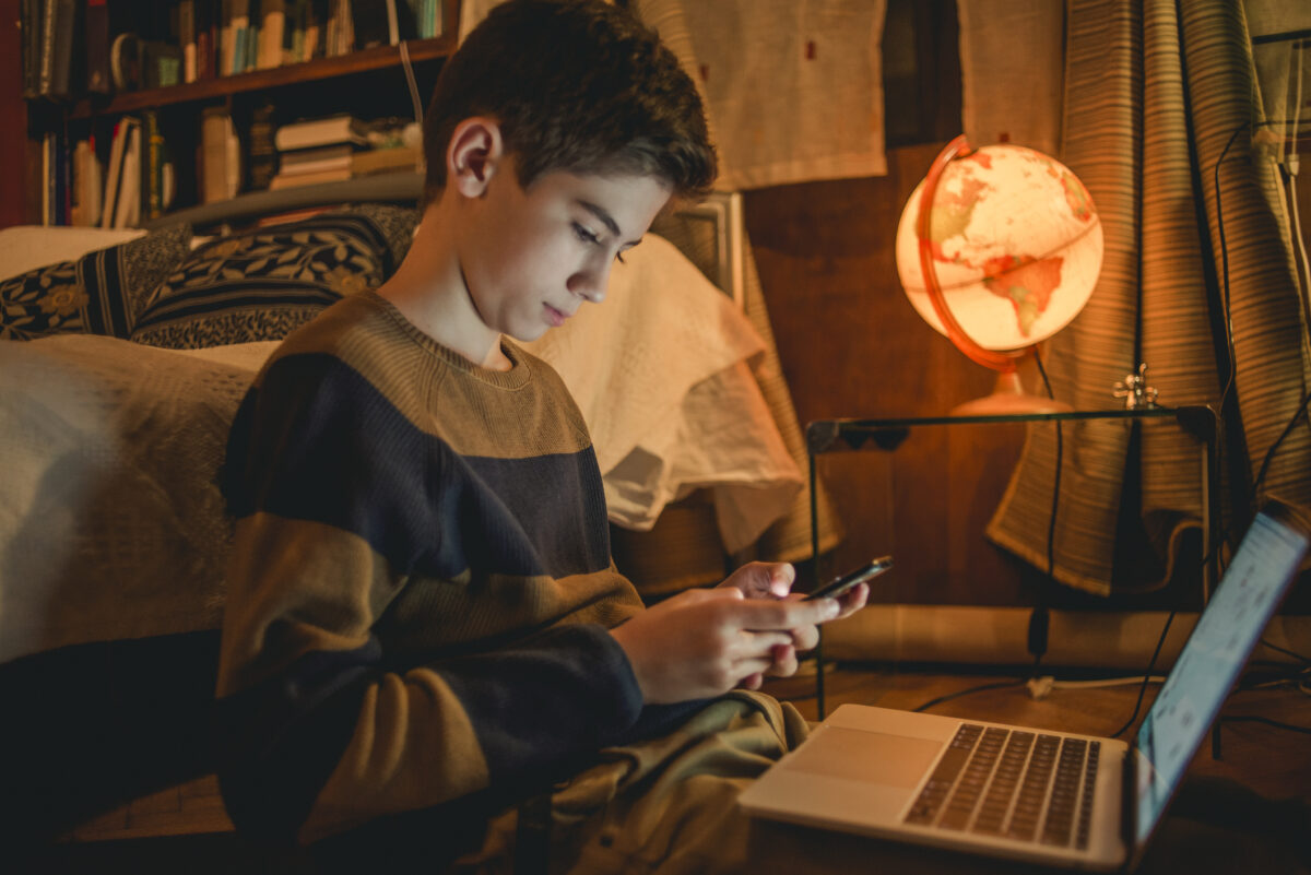 Young teenager using Discord on his phone and computer