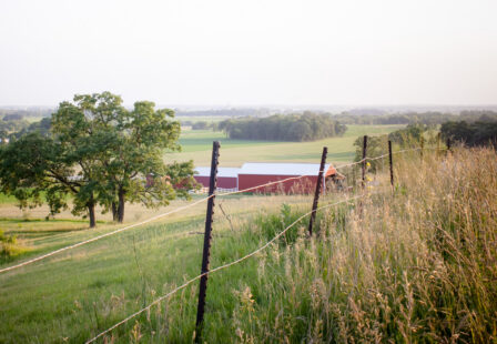 Red metal outbuilding surrounded by fields on a rural Wisconsin property
