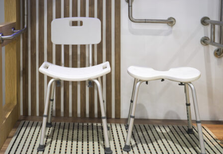 Accessible nursing home shower area with shower chairs and grab bars.