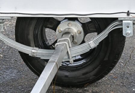 Close-up of trailer wheel, axle, and suspension assembly